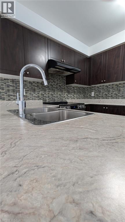 Kitchen with dark brown cabinetry, freestanding refrigerator, decorative backsplash, and black range with electric cooktop - 19 Cromarty Avenue, Caledonia, ON - Indoor Photo Showing Kitchen With Double Sink