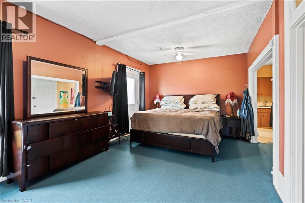 Bedroom featuring a textured ceiling, carpet flooring, a ceiling fan, and connected bathroom - 5368 Menzie Street, Niagara Falls, ON - Indoor Photo Showing Bedroom