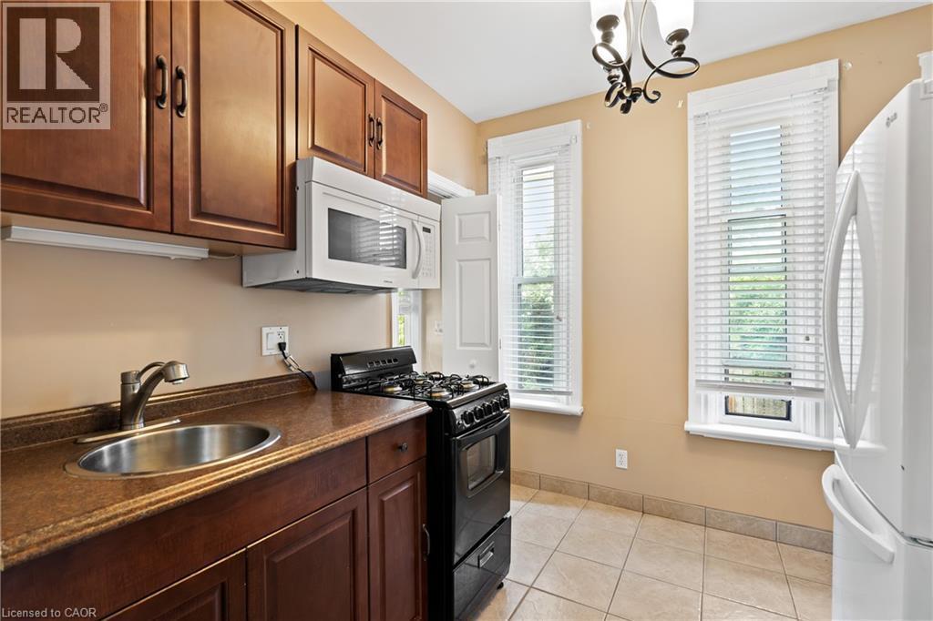 Kitchen featuring white appliances, dark countertops, plenty of natural light, and a chandelier - 5368 Menzie Street, Niagara Falls, ON - Indoor Photo Showing Kitchen