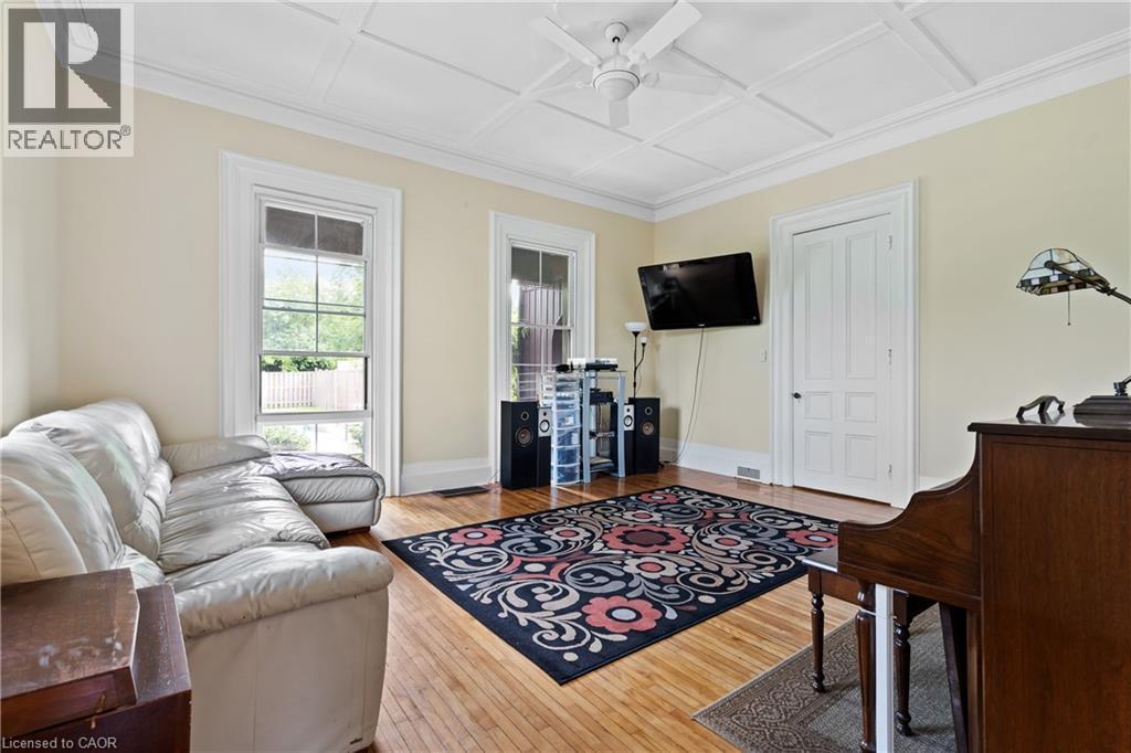 Living area featuring a ceiling fan, coffered ceiling, wood finished floors, and crown molding - 5368 Menzie Street, Niagara Falls, ON - Indoor Photo Showing Other Room