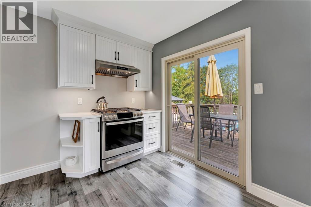 Kitchen featuring stainless steel range with gas stovetop, under cabinet range hood, light wood finished floors, and white cabinets - 1565 Old Brock Street, Vittoria, ON - Indoor Photo Showing Kitchen