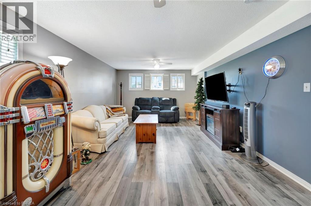 Living room featuring light wood-style floors, a textured ceiling, and a ceiling fan - 1565 Old Brock Street, Vittoria, ON - Indoor