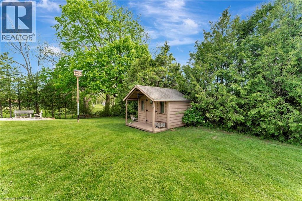 View of green lawn with view of wooded area and an outbuilding - 1565 Old Brock Street, Vittoria, ON - Outdoor