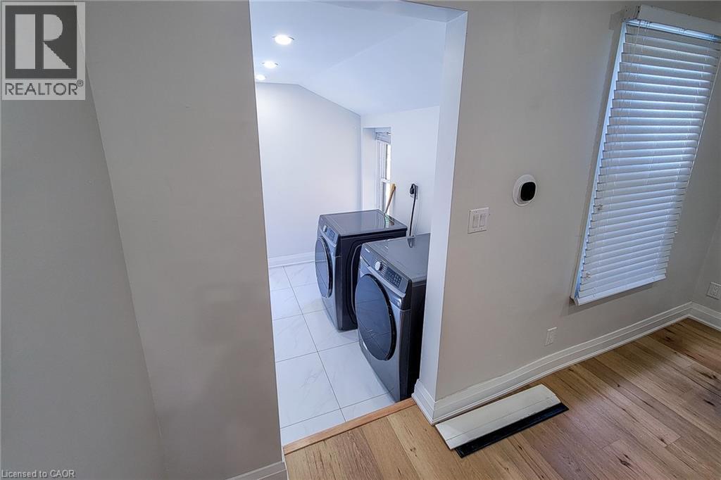 Laundry room featuring separate washer and dryer, wood finished floors, vaulted ceiling, and recessed lighting - 51 West Avenue N, Hamilton, ON - Indoor Photo Showing Laundry Room