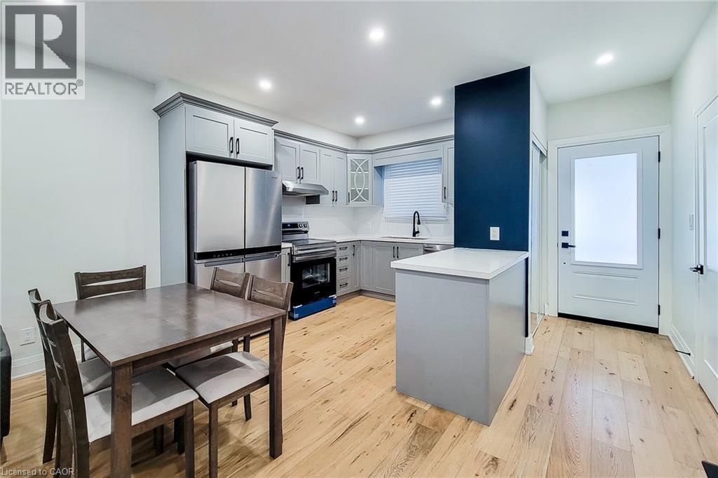 Kitchen with gray cabinets, appliances with stainless steel finishes, light wood-style floors, light countertops, and recessed lighting - 51 West Avenue N, Hamilton, ON - Indoor