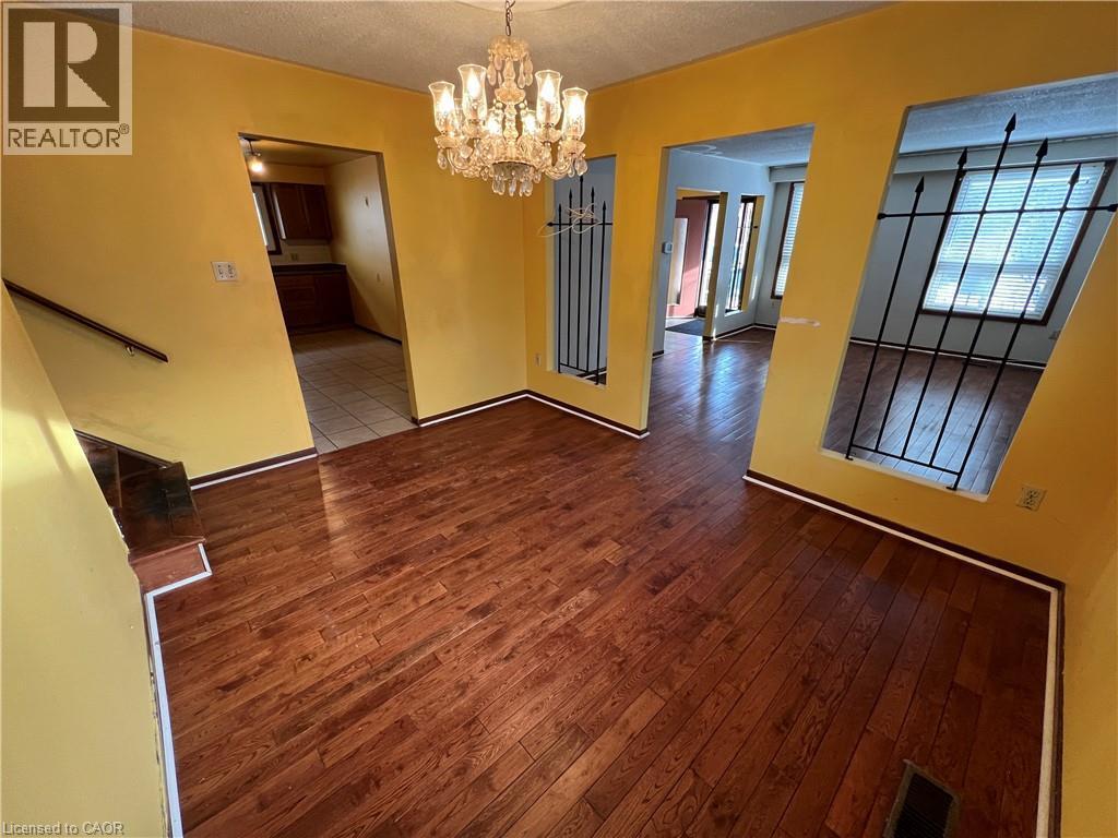 Unfurnished dining area featuring suspended lighting, wood-type flooring, and a textured ceiling - 185 Lavina Crescent, Hamilton, ON - Indoor Photo Showing Other Room