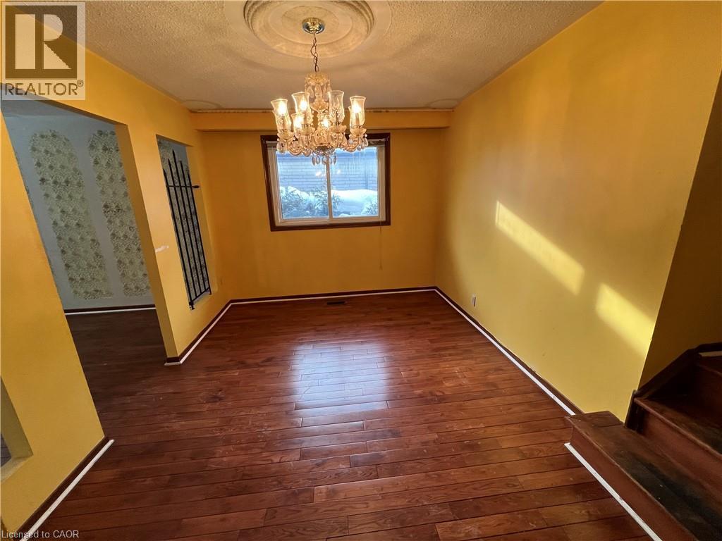 Unfurnished dining area featuring dark wood-type flooring, a chandelier, and a textured ceiling - 185 Lavina Crescent, Hamilton, ON - Indoor Photo Showing Other Room
