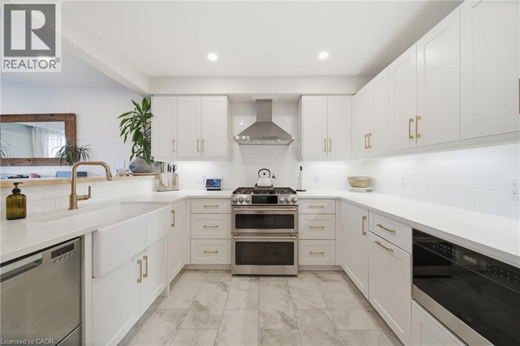 Kitchen featuring stainless steel appliances, tasteful backsplash, white cabinets, recessed lighting, and wall chimney exhaust hood - 136 Braemar Avenue, Caledonia, ON - Indoor Photo Showing Kitchen With Upgraded Kitchen