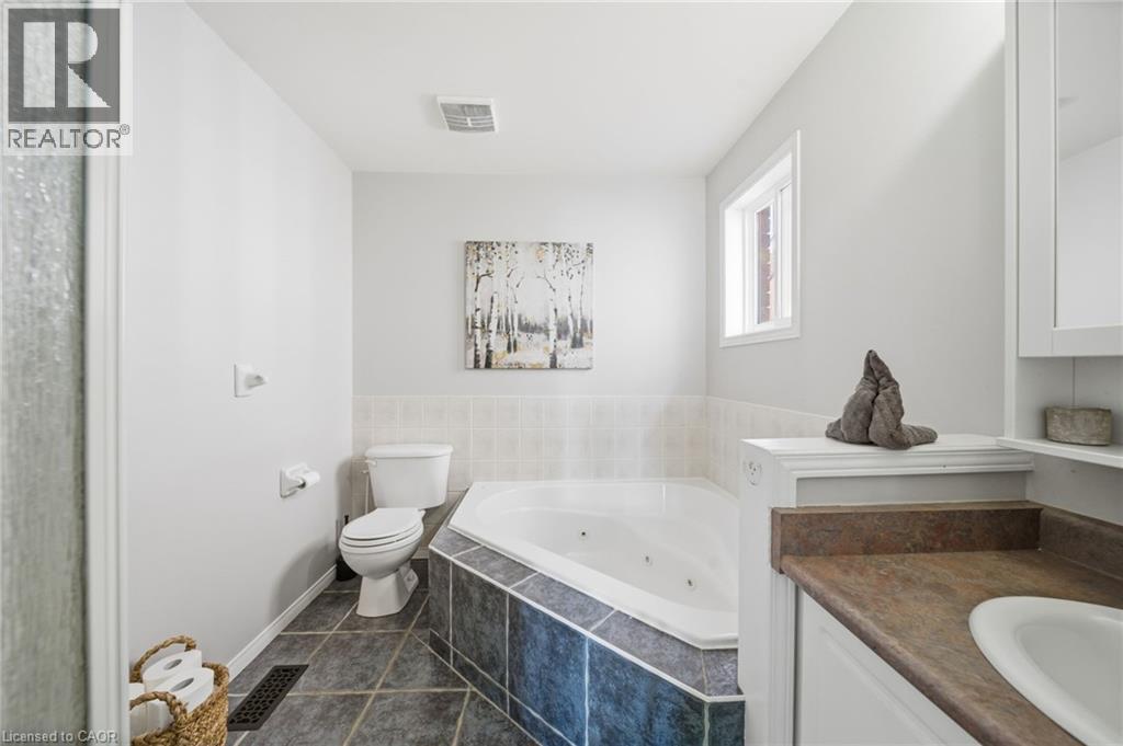 Full bath with dark tile patterned flooring, vanity, and a jetted tub - 136 Braemar Avenue, Caledonia, ON - Indoor Photo Showing Bathroom