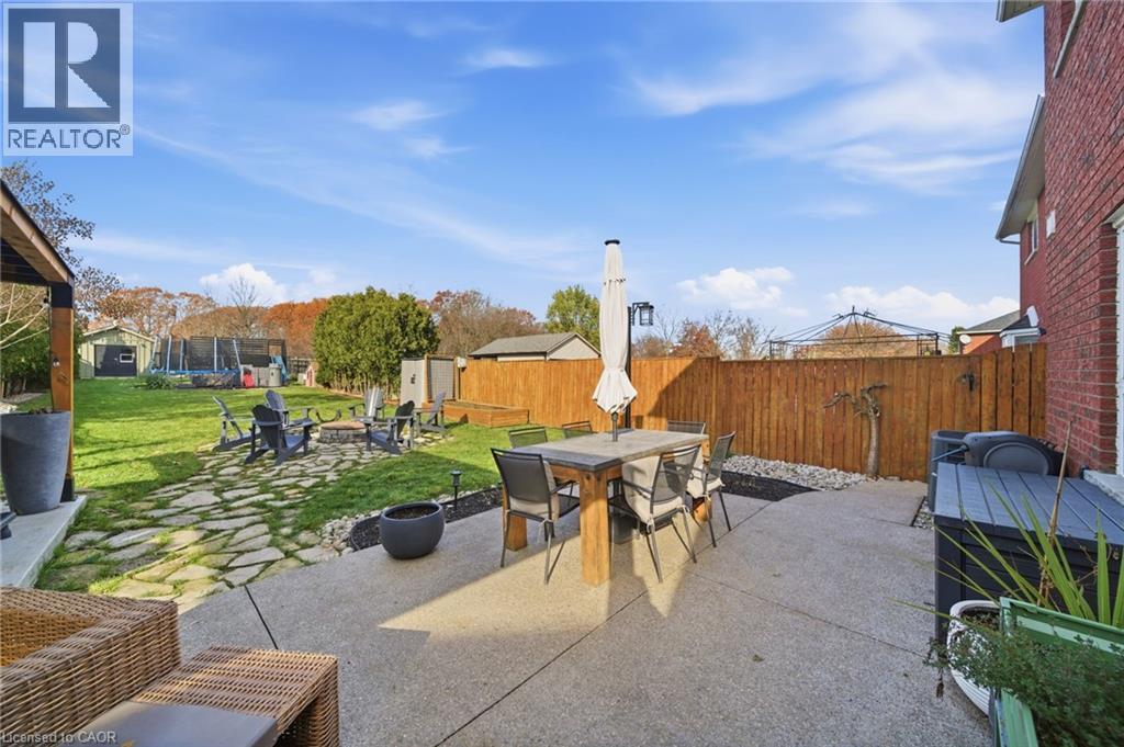 Fenced backyard with a trampoline, outdoor dining area, a patio, and an outdoor fire pit - 136 Braemar Avenue, Caledonia, ON - Outdoor