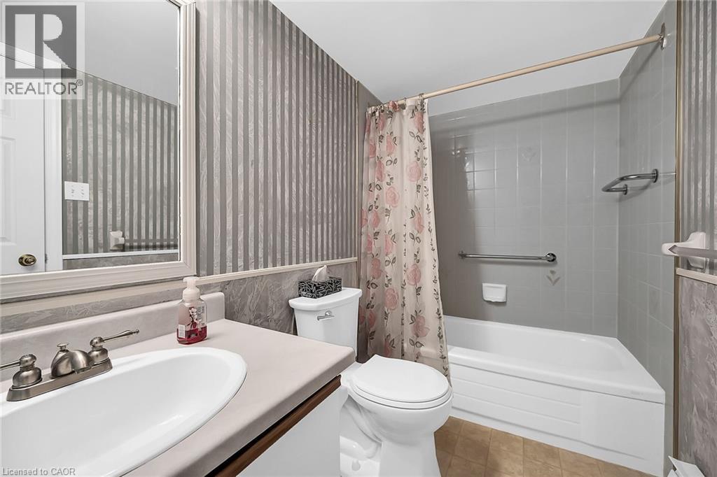 Bathroom featuring tile patterned floors, vanity, shower / bathtub combination with curtain, and toilet - 416 Limeridge Road E Unit# 309, Hamilton, ON - Indoor Photo Showing Bathroom