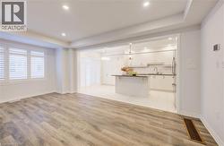 Unfurnished living room featuring light wood-style floors, recessed lighting, and a tray ceiling -