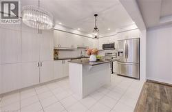 Kitchen featuring appliances with stainless steel finishes, a kitchen island, decorative backsplash, decorative light fixtures, and light tile patterned floors -