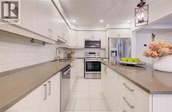 Kitchen with stainless steel appliances, backsplash, light tile patterned floors, dark stone countertops, and hanging light fixtures -
