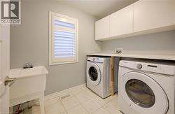 Washroom with light tile patterned floors, washing machine and clothes dryer, and cabinet space -
