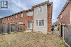 Rear view of property featuring a fenced backyard, brick siding, and entry steps -