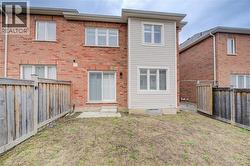 Back of house with a fenced backyard and brick siding -