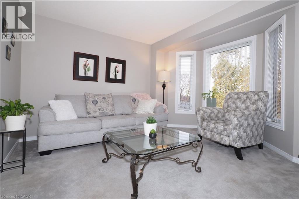 Carpeted living area featuring full length bay windows - 511 Oakvale Drive Unit# 1, Waterloo, ON - Indoor Photo Showing Living Room