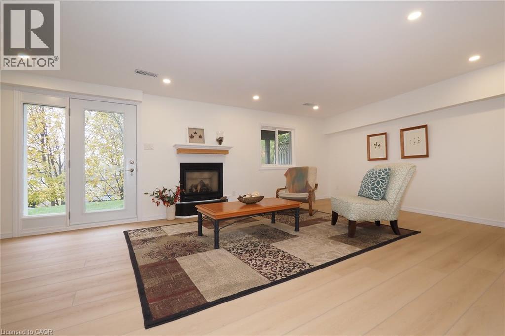 Basement recreation room with recessed lighting, gas fireplace, and French doors to back yard patio - 511 Oakvale Drive Unit# 1, Waterloo, ON - Indoor Photo Showing Living Room With Fireplace