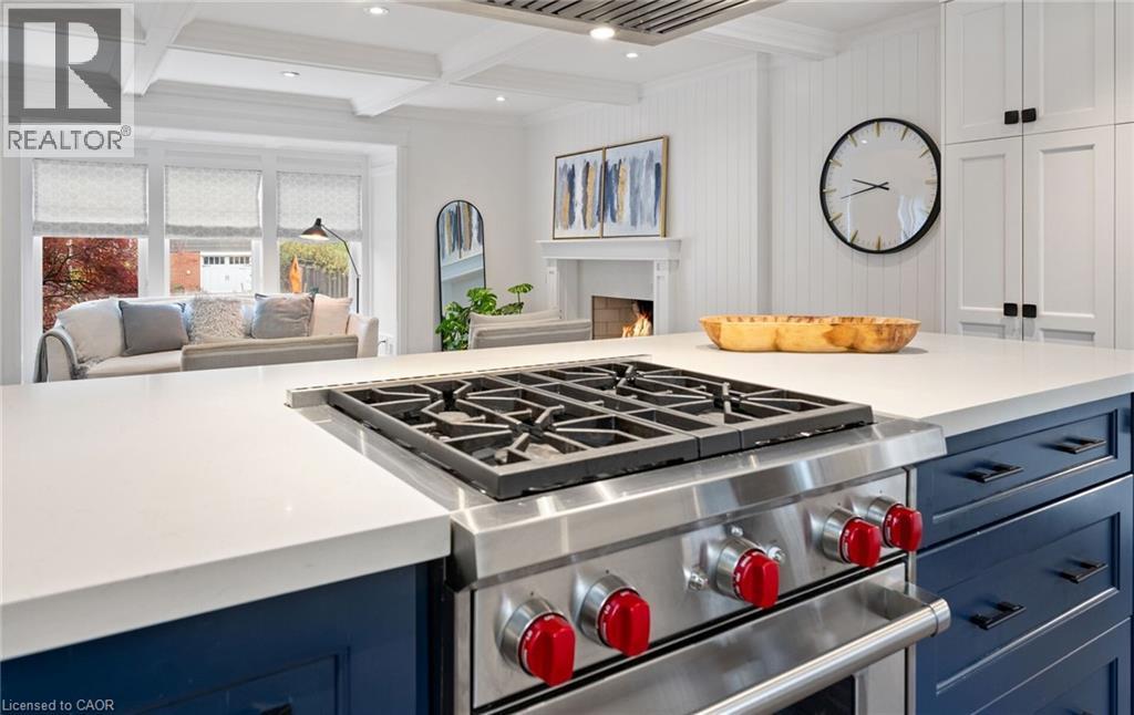 Kitchen featuring blue cabinets, designer range, open floor plan, a warm lit fireplace, and beam ceiling - 735 George Street, Burlington, ON - Indoor Photo Showing Kitchen
