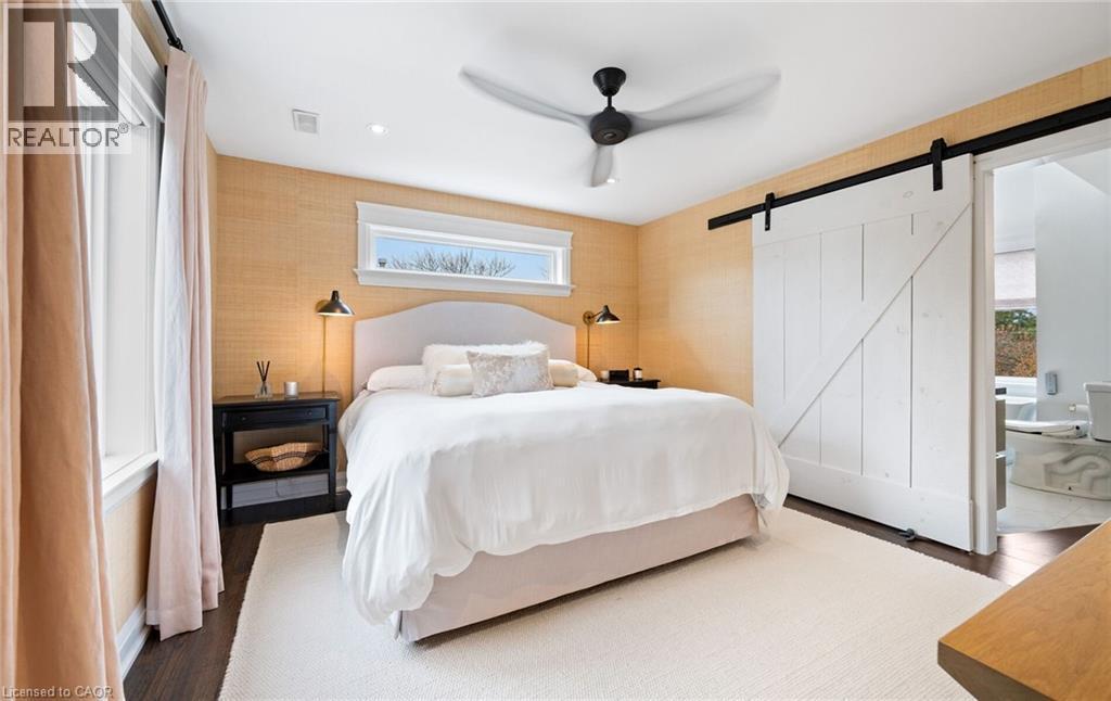 Bedroom featuring wood finished floors, ensuite bath, ceiling fan, and a barn door - 735 George Street, Burlington, ON - Indoor Photo Showing Bedroom