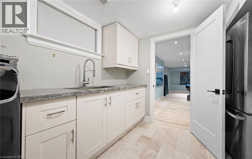 Kitchen featuring freestanding refrigerator, light stone countertops, white cabinetry, and washer / dryer - 735 George Street, Burlington, ON - Indoor Photo Showing Kitchen