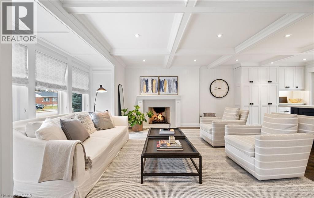 Living area featuring beamed ceiling, recessed lighting, a warm lit fireplace, coffered ceiling, and light wood-type flooring - 735 George Street, Burlington, ON - Indoor Photo Showing Living Room With Fireplace