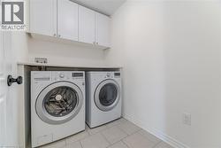 Laundry room with light tile patterned floors, cabinet space, and washer and dryer -