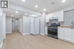 Kitchen with white cabinetry, electric range, freestanding refrigerator, light wood-style floors, and recessed lighting -