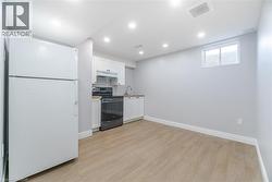 Kitchen with freestanding refrigerator, white cabinets, stainless steel range with electric stovetop, light wood-type flooring, and recessed lighting -