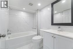 Bathroom featuring tile walls, light marble finish flooring, shower combination, vanity, and recessed lighting -