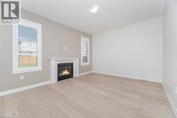 Unfurnished living room featuring healthy amount of natural light, light wood-style flooring, and a glass covered fireplace -