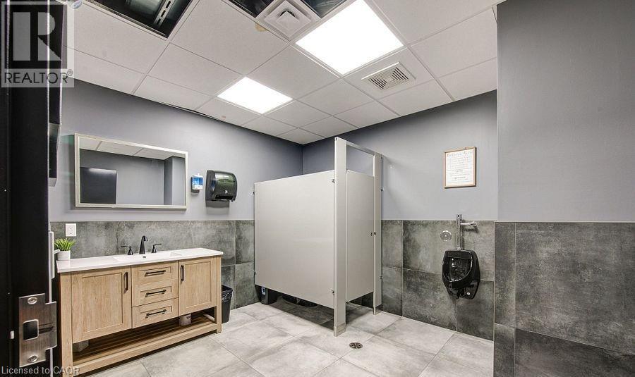 Bathroom featuring a drop ceiling, a wainscoted wall, vanity, and tile walls - 55 Progress Drive E, Aylmer, ON