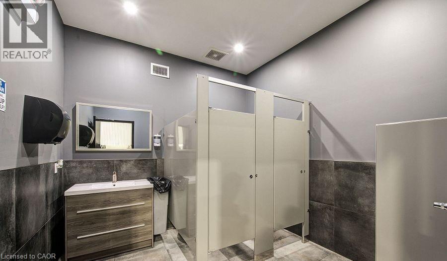 Full bathroom with tile walls, wainscoting, vanity, and a stall shower - 55 Progress Drive E, Aylmer, ON