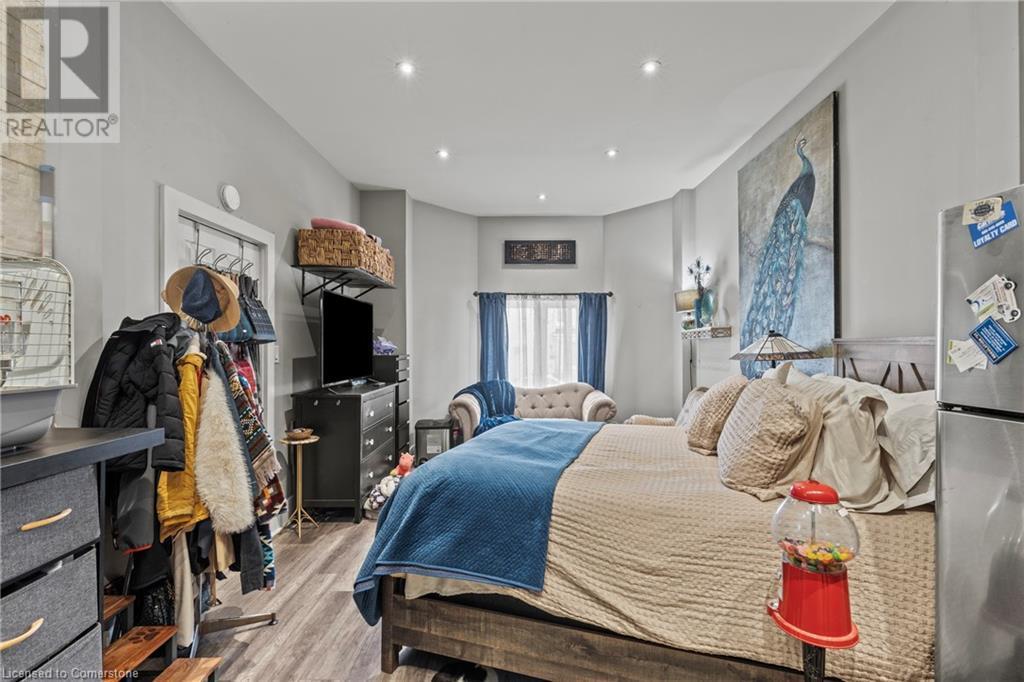 Bedroom with wood finished floors, recessed lighting, and freestanding refrigerator - 181 West Avenue N, Hamilton, ON - Indoor Photo Showing Bedroom