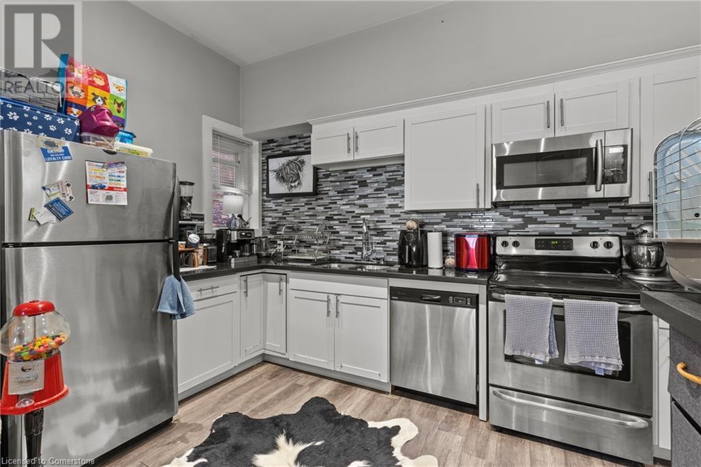 Kitchen with stainless steel appliances, backsplash, a sink, dark countertops, and light wood finished floors - 181 West Avenue N, Hamilton, ON - Indoor Photo Showing Kitchen With Upgraded Kitchen