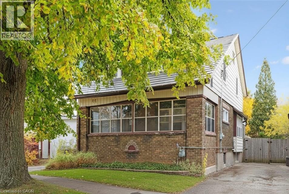 View of side of home with brick siding, a gate, and a sunroom - 41 Rose Street, Kitchener, ON - Outdoor