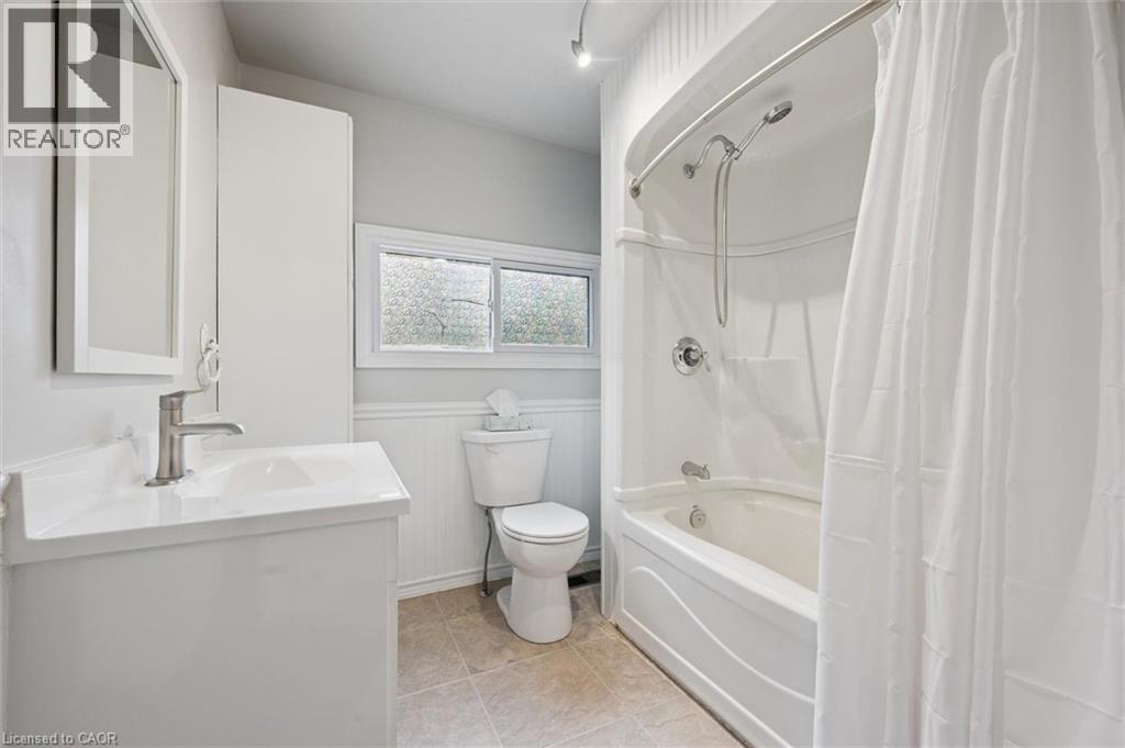 Full bathroom featuring shower / bath combo with shower curtain, vanity, wainscoting, and light tile patterned flooring - 41 Rose Street, Kitchener, ON - Indoor Photo Showing Bathroom