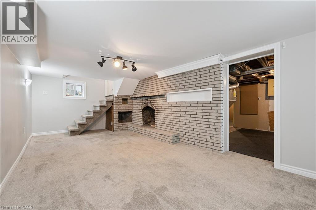 Unfurnished living room with a fireplace, carpet floors, and brick wall - 41 Rose Street, Kitchener, ON - Indoor