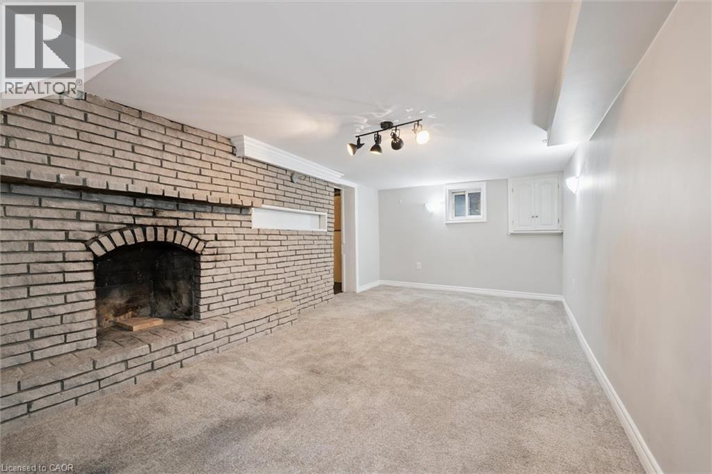 Unfurnished living room featuring light carpet, a brick fireplace, and track lighting - 41 Rose Street, Kitchener, ON - Indoor With Fireplace