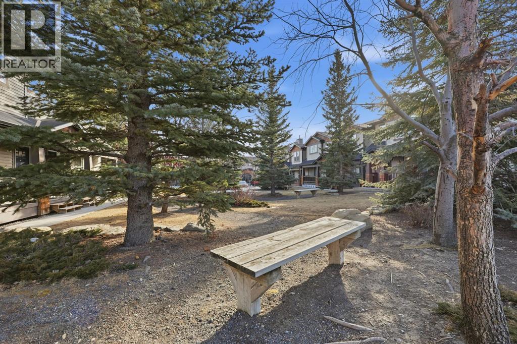 Cozy amenity space with benches and trees that looks beautiful in the summer - 117 Panatella Park Nw, Calgary, AB - Outdoor