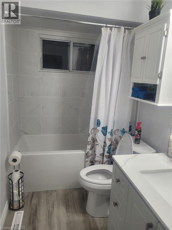 Full bath with shower / bath combination with curtain, wood finished floors, and vanity - 89 Deschene Avenue, Hamilton, ON - Indoor Photo Showing Bathroom