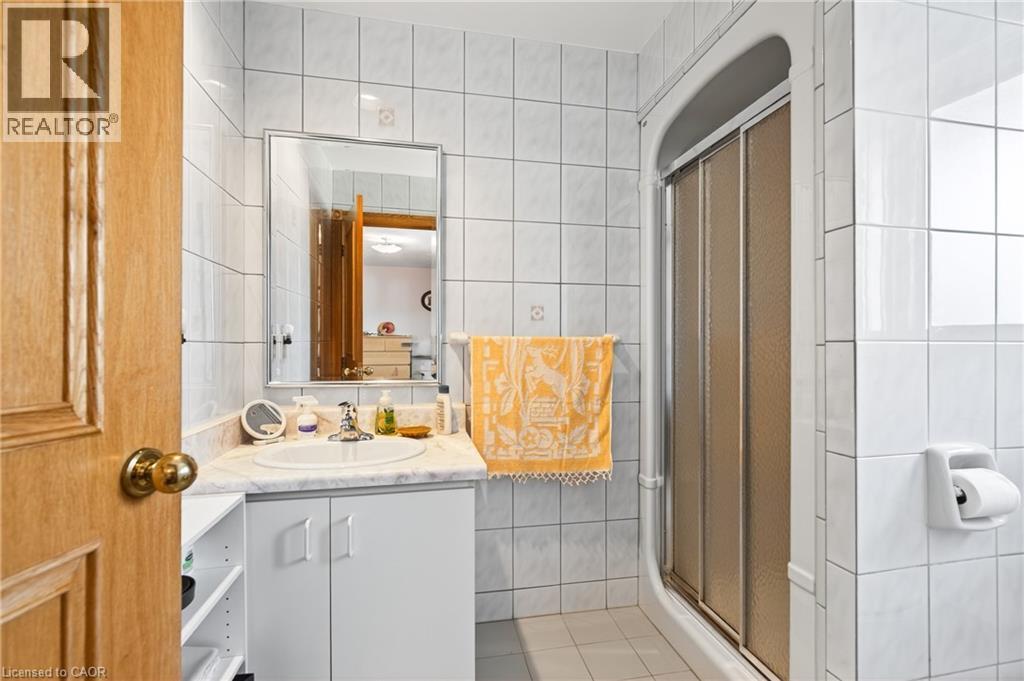 Full bath featuring tile walls, vanity, light tile patterned floors, and a shower stall - 79 Maple Drive, Hamilton, ON - Indoor Photo Showing Bathroom