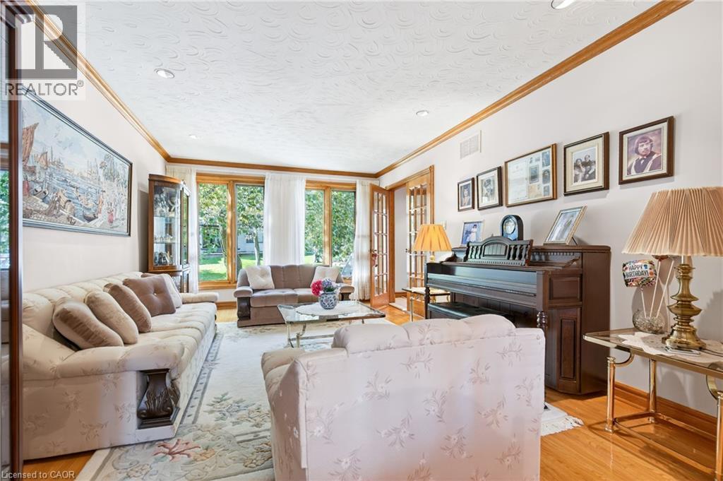 Living area featuring crown molding, light wood-type flooring, and a textured ceiling - 79 Maple Drive, Hamilton, ON - Indoor Photo Showing Living Room