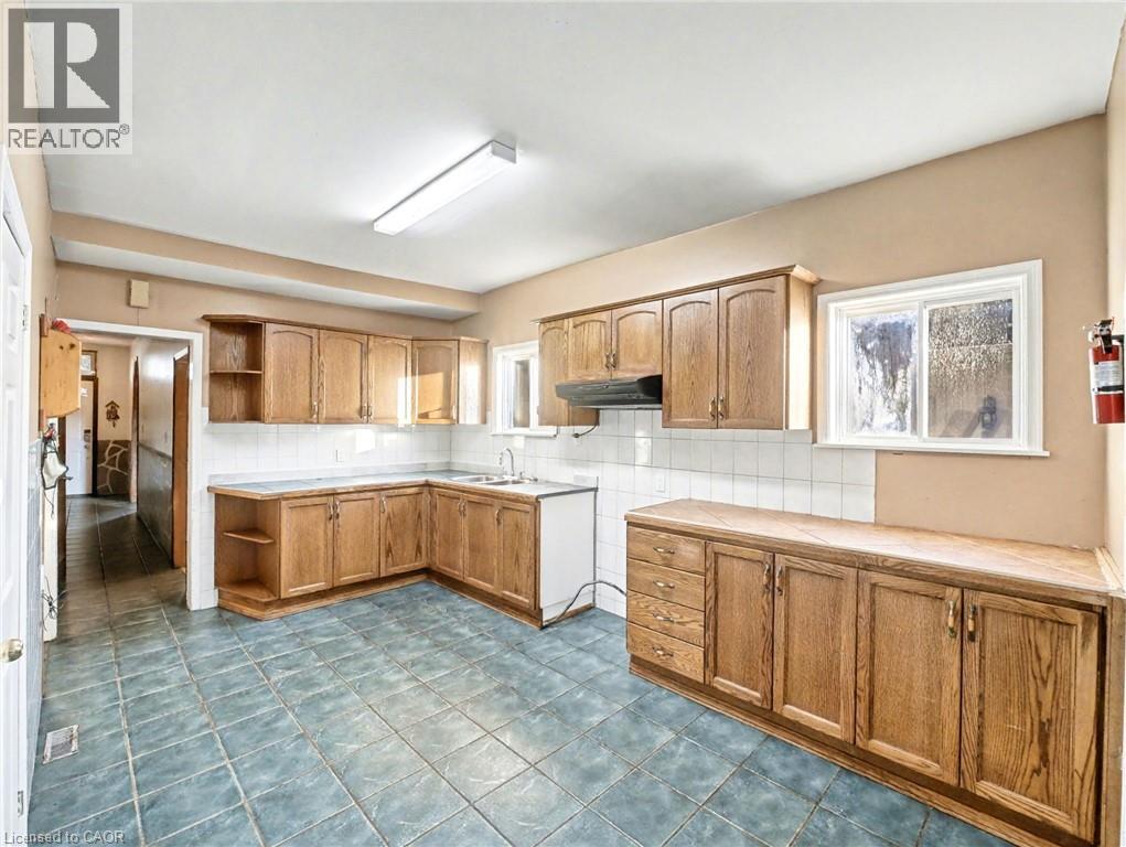 Kitchen featuring open shelves, backsplash, brown cabinets, and healthy amount of natural light - 23 Oak Avenue, Hamilton, ON - Indoor Photo Showing Kitchen