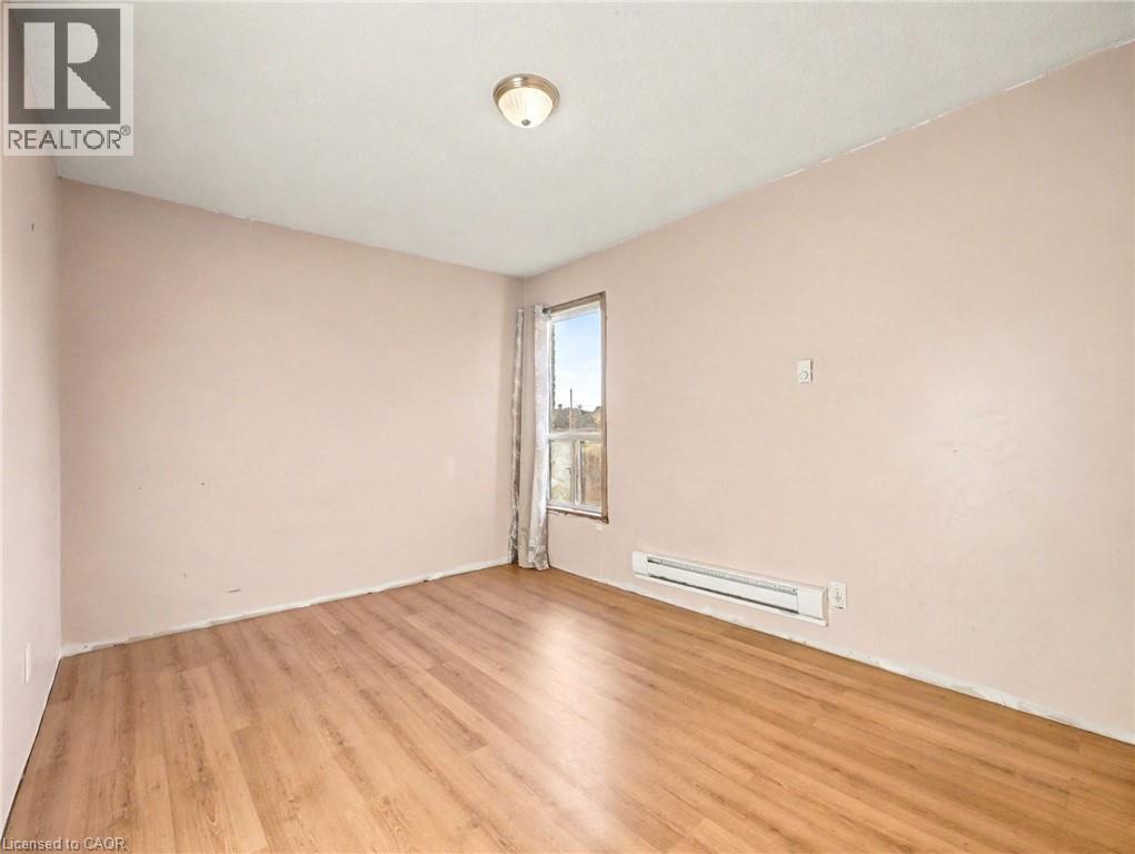 Unfurnished room featuring light wood-style flooring and a baseboard radiator - 23 Oak Avenue, Hamilton, ON - Indoor Photo Showing Other Room