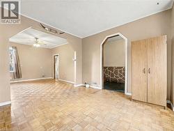 Empty room featuring ornamental molding, arched walkways, and a ceiling fan -