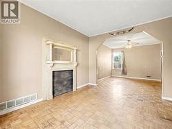 Unfurnished living room with arched walkways, ornamental molding, and a ceiling fan -