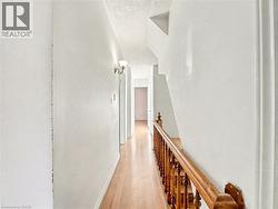 Hall featuring light wood-style flooring, an upstairs landing, and a textured ceiling -