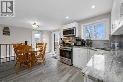 Kitchen with stainless steel appliances, light stone counters, decorative backsplash, white cabinetry, and recessed lighting -